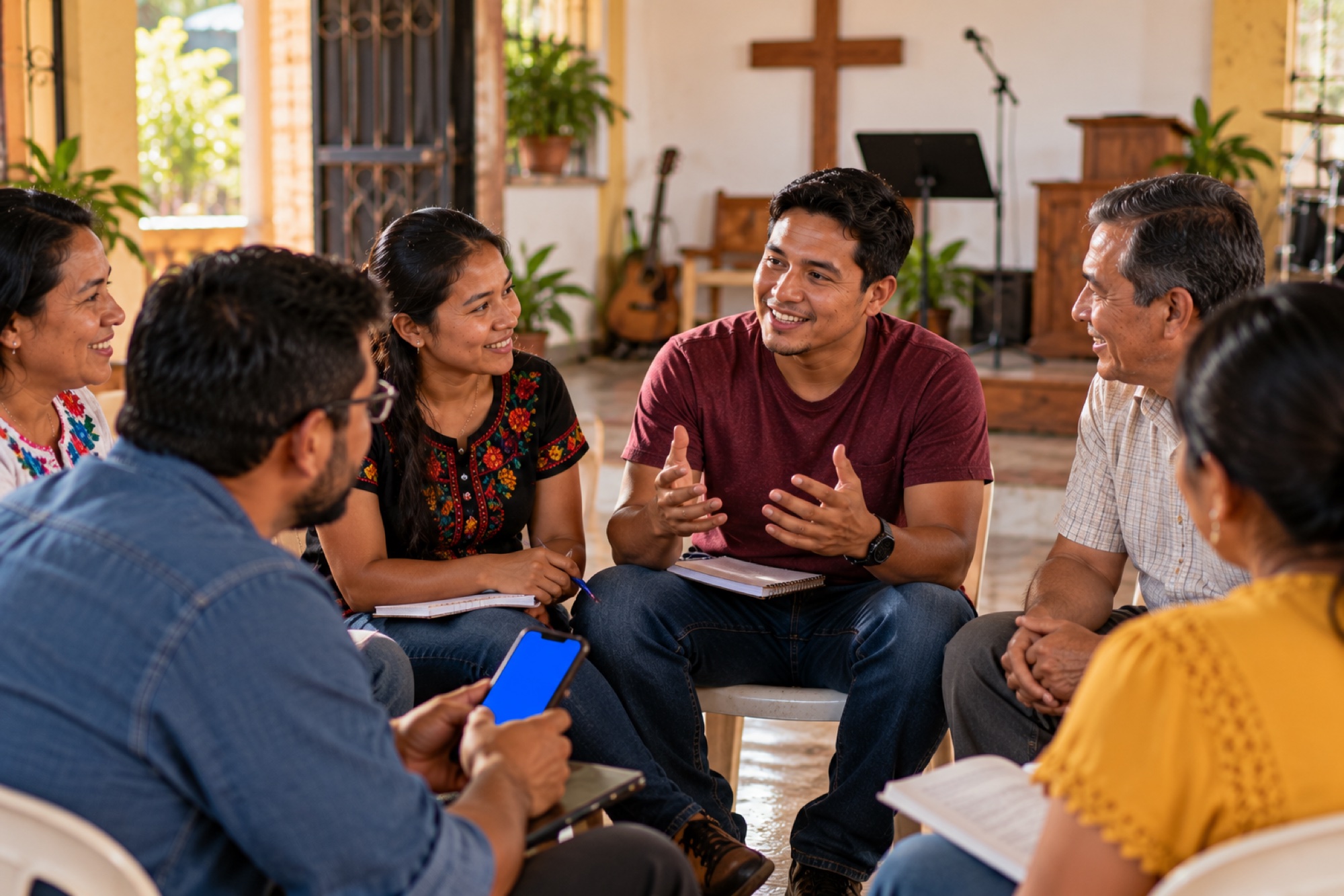 A small group sits in a church room, talking over notebooks and a phone.